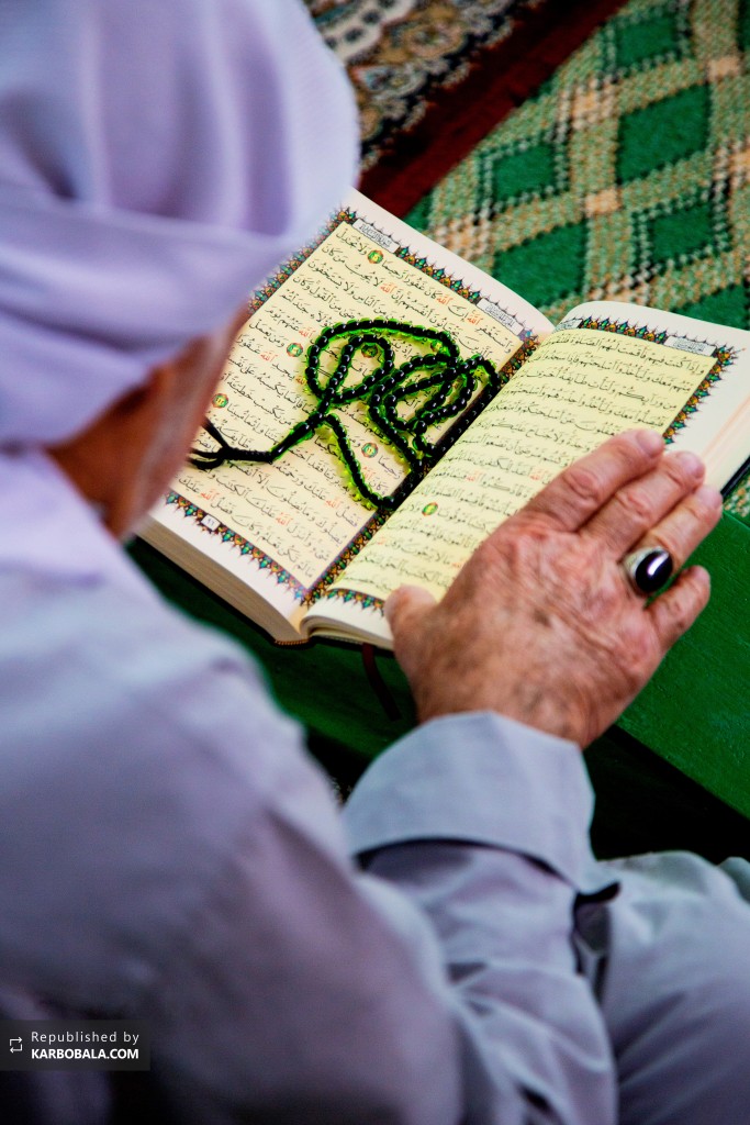 زائر حسینی در حال قرائت قرآن در کربلای معلی